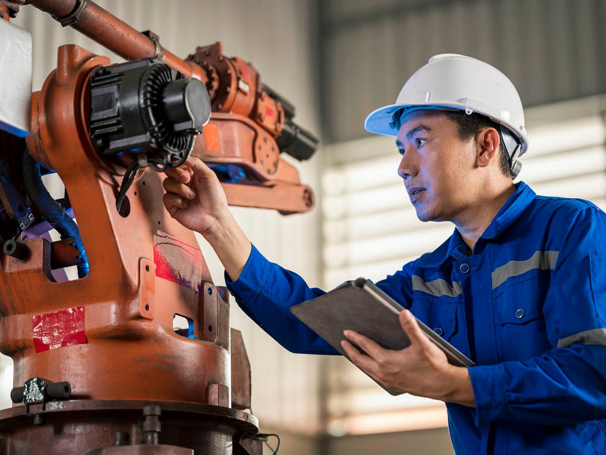 Senior Engineer testing of an industrial robot accuracy and repeatability in off and online by using digital tablet.