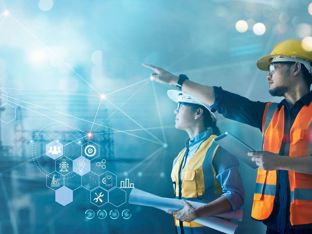 Male and female industrial engineers using tablet at power plant.