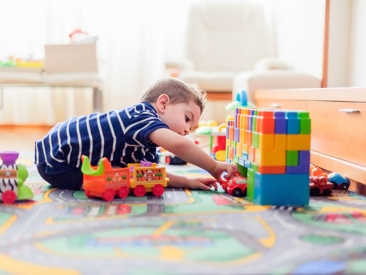 Little child, 2 years, playing with small cars and toys at home