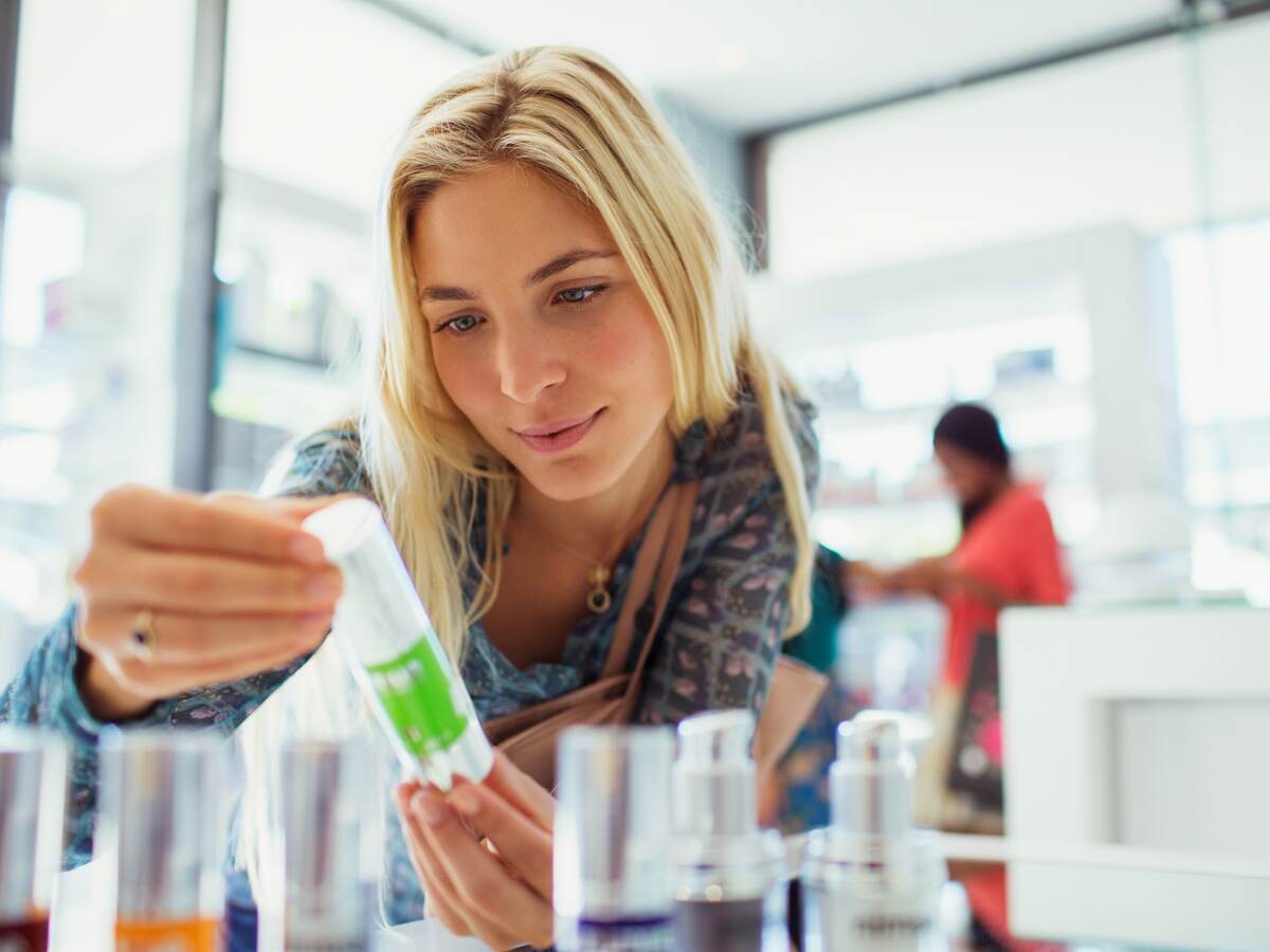 Woman examining skincare product in drugstore.