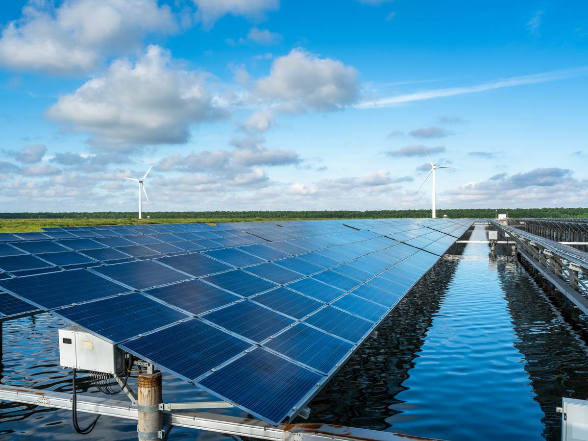 The solar photovoltaic power station on the water surface and the wind turbine in the distance.