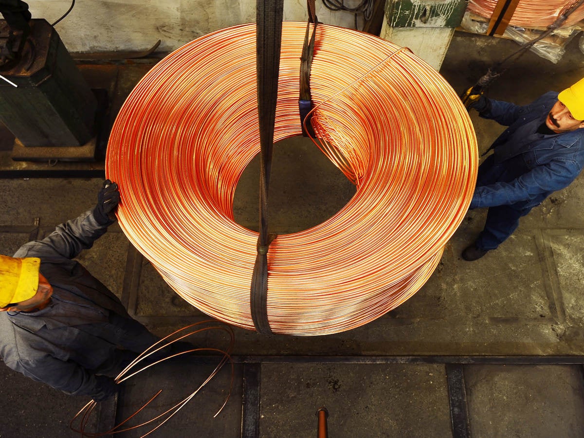 Workers moving roll of copper wire.