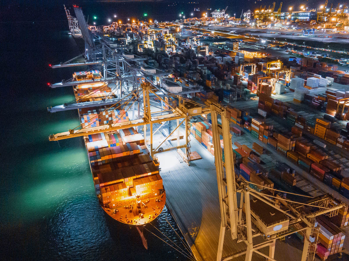 A cargo ship docked with many shipping containers