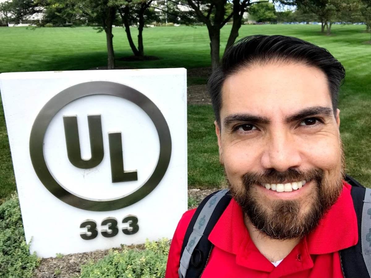 Jean Levya stands next to sign at UL Solutions main campus. 