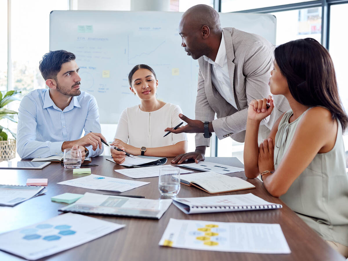 Four people attending a meeting in an office with lots of bright windows