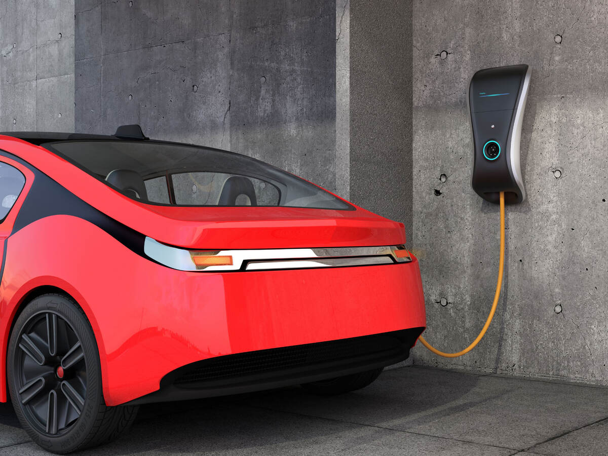 A red electric vehicle is charging at a wall charger