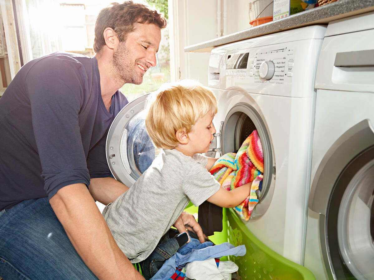 A parent and child loading a dryer