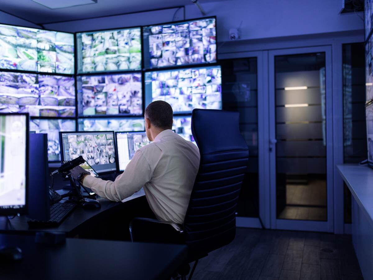 Man working in surveillance room and looking at monitors