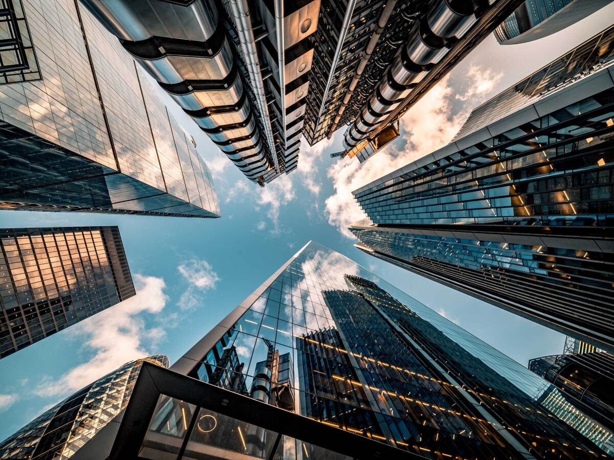 Upward view of the blue sky surrounded by towering skyscrapers