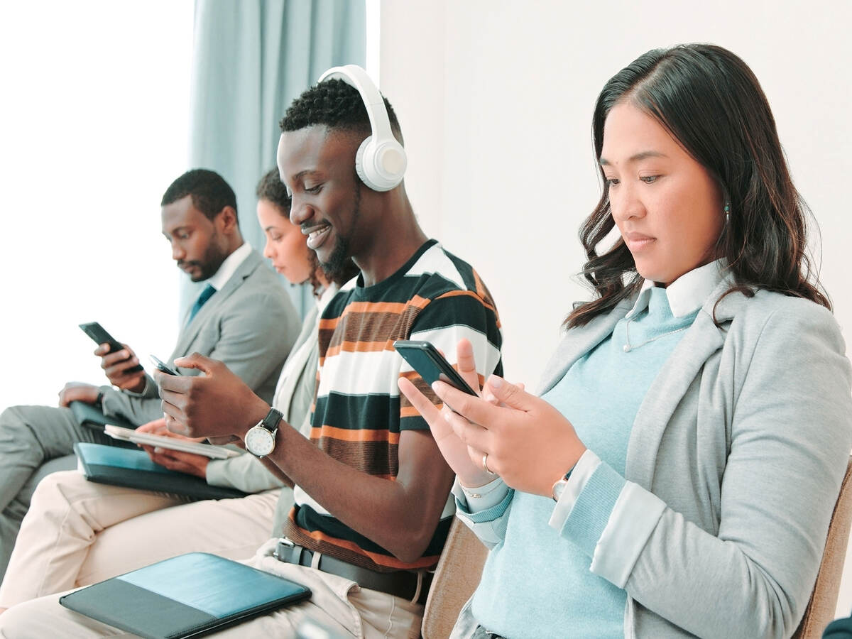 Several people in a waiting room and working on their smartphones