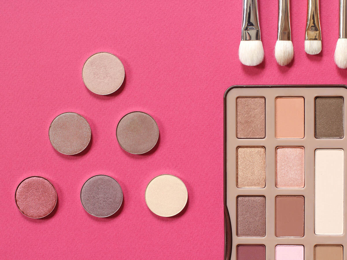 Palette of eye shadow in gold tones on a pink background