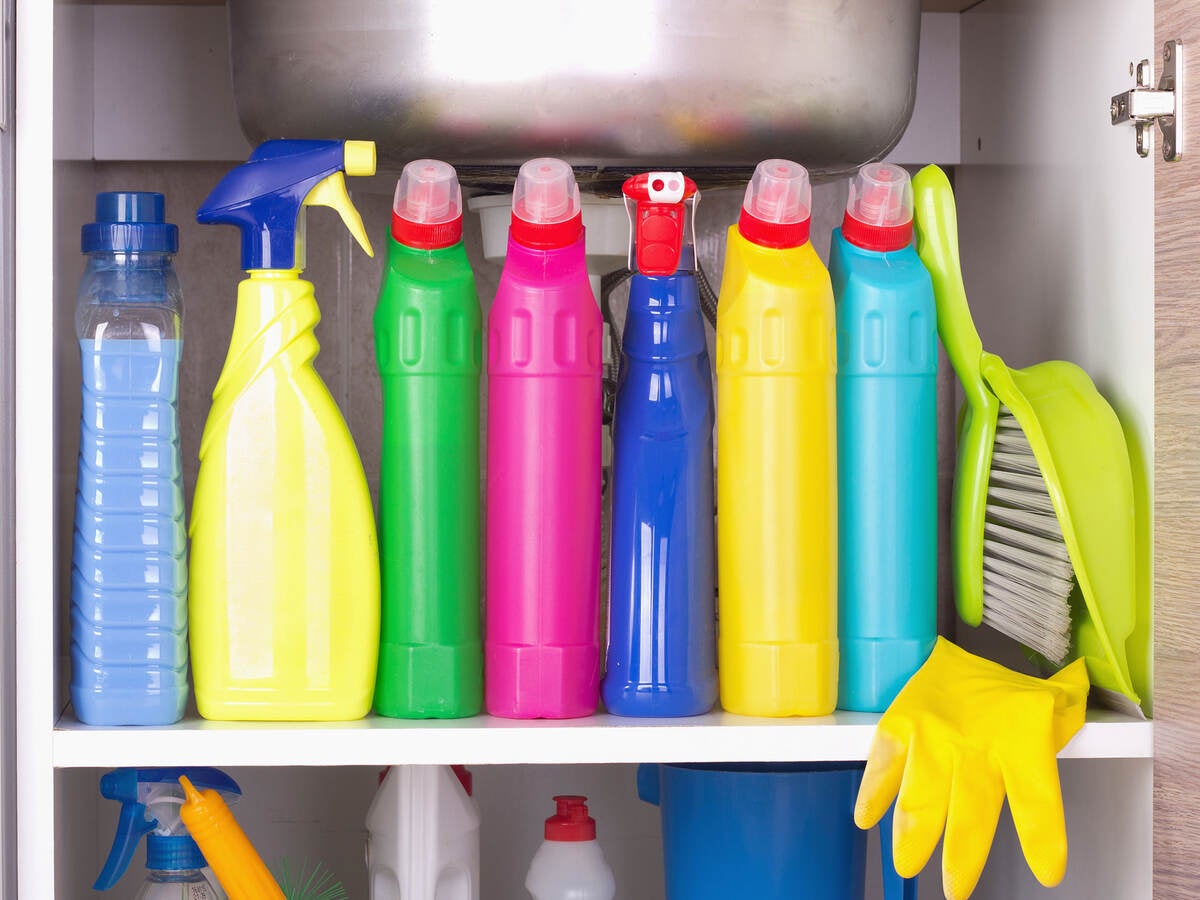 Several cleaning products, glove and dustpan on a shelf in a storage closet