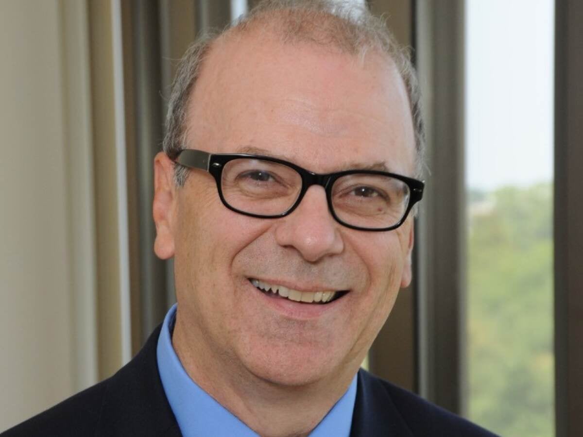 Headshot of Ken Boyce wearing glasses in dark suite with blue shirt. 