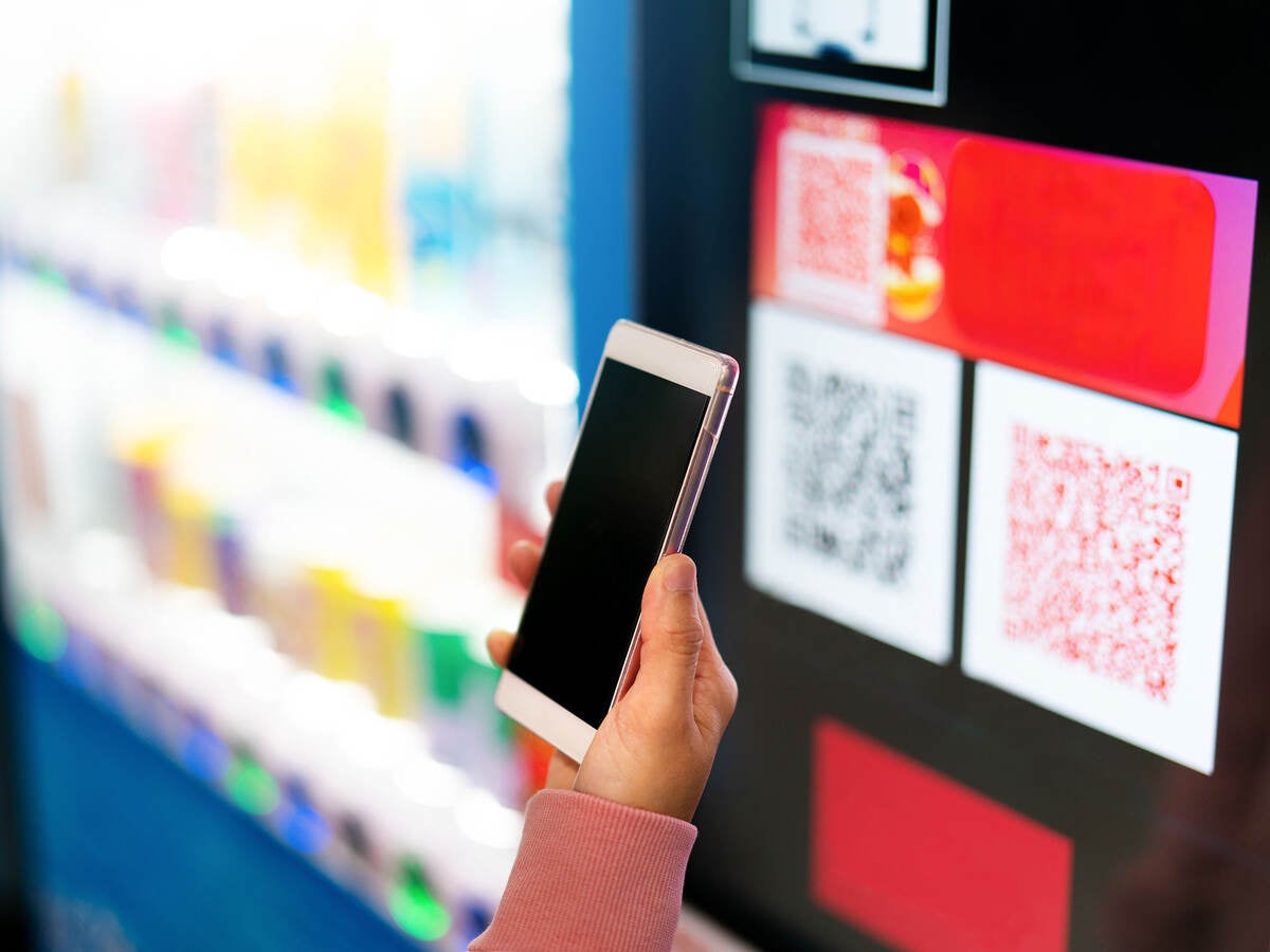 A person scanning a QR code for payment at a vending machine