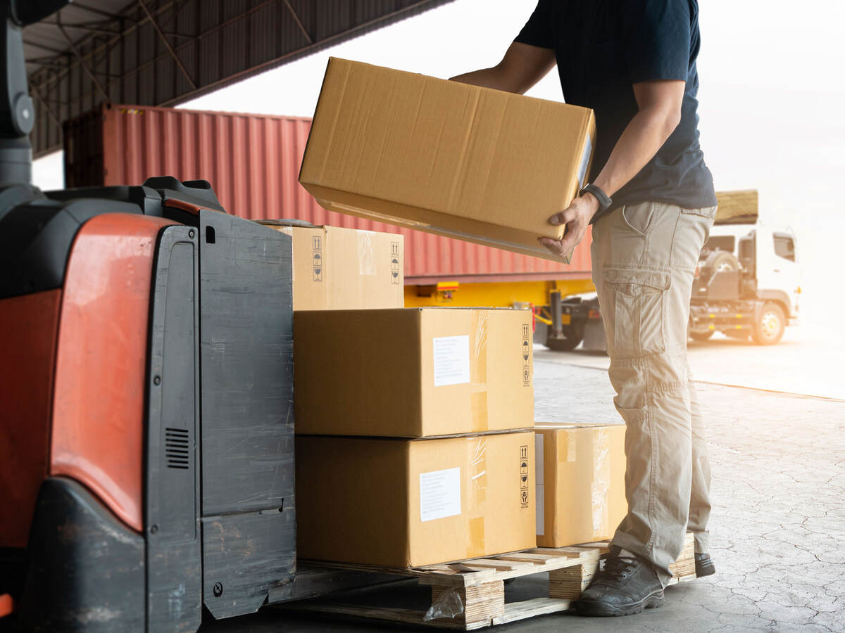 A warehouse worker loading boxes onto a pallet