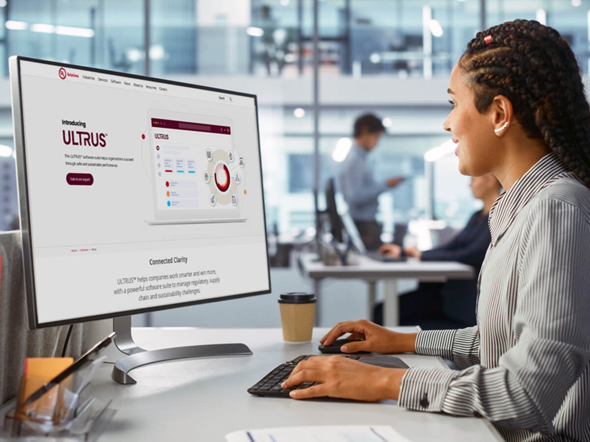 Woman viewing ULTRUS website on computer at her desk sitting in glass-walled office 