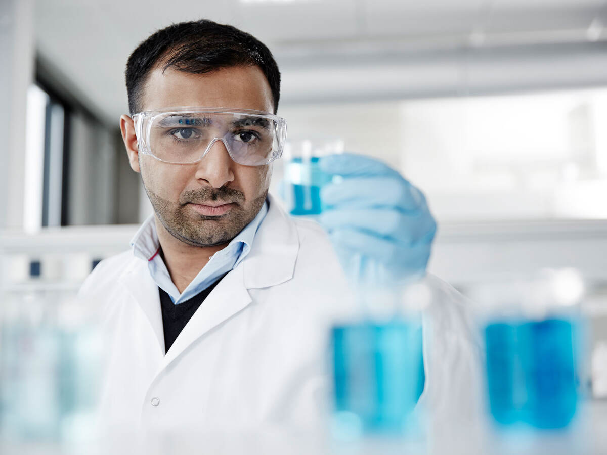 A scientist examining a blue liquid in a beaker