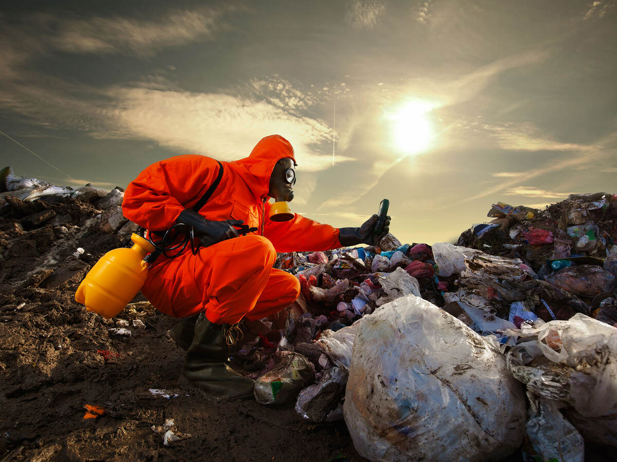 A person wearing orange protective equipment and measuring pollution