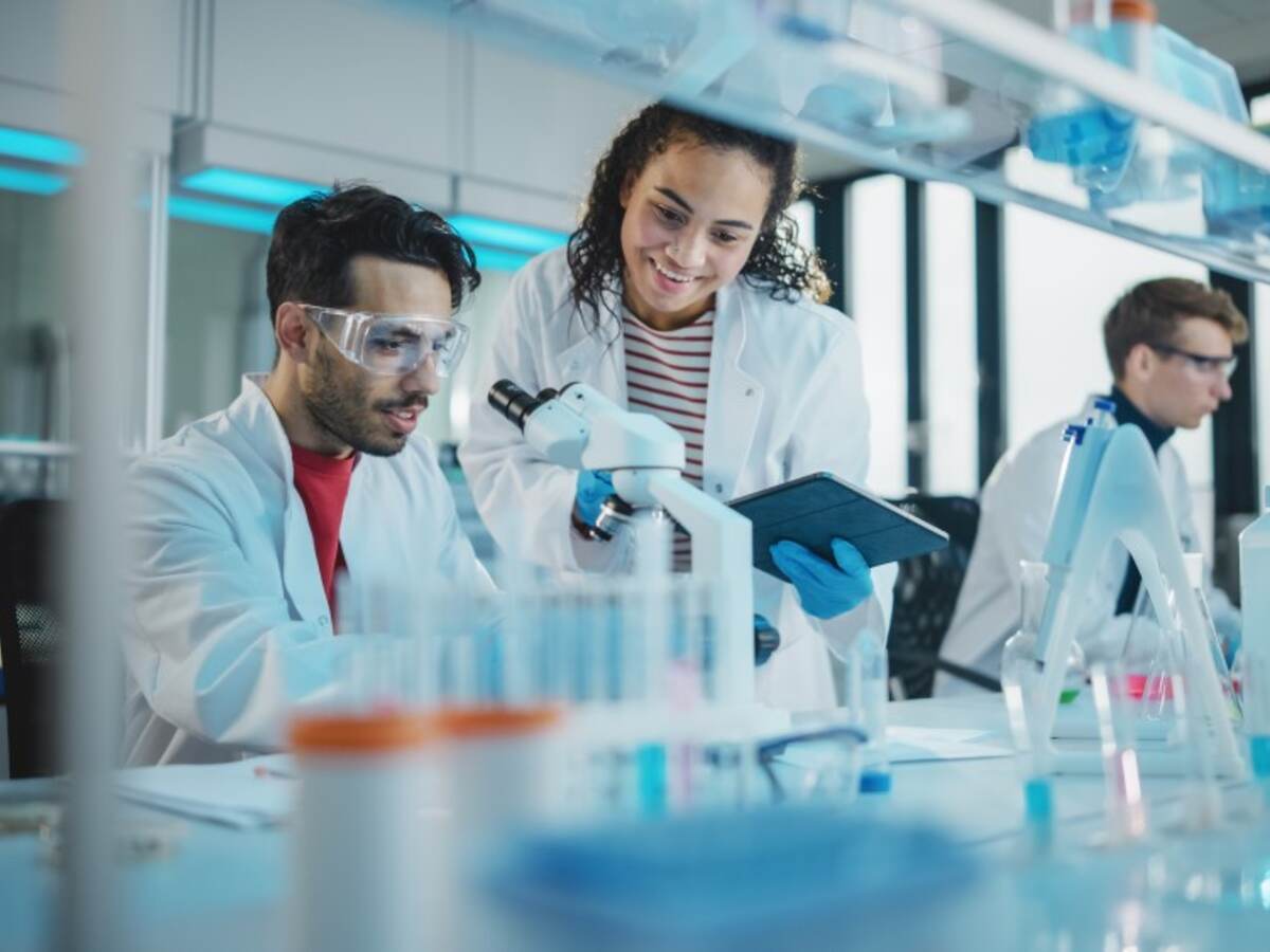 Scientists talking in lab by microscope. 