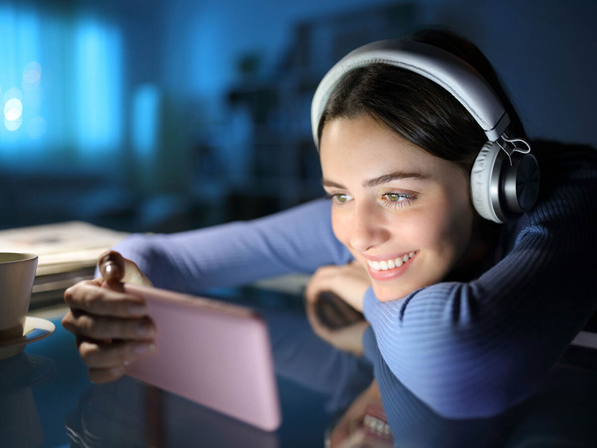 Woman wearing headphones and watching media on mobile phone