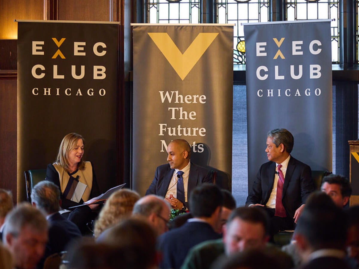 Jenny Scanlon speaks with panelists on stage at Chicago Executives' Club event. 