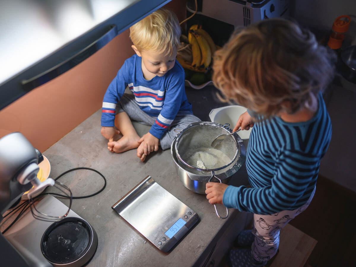 Two children using a food scale to measure out ingredients 