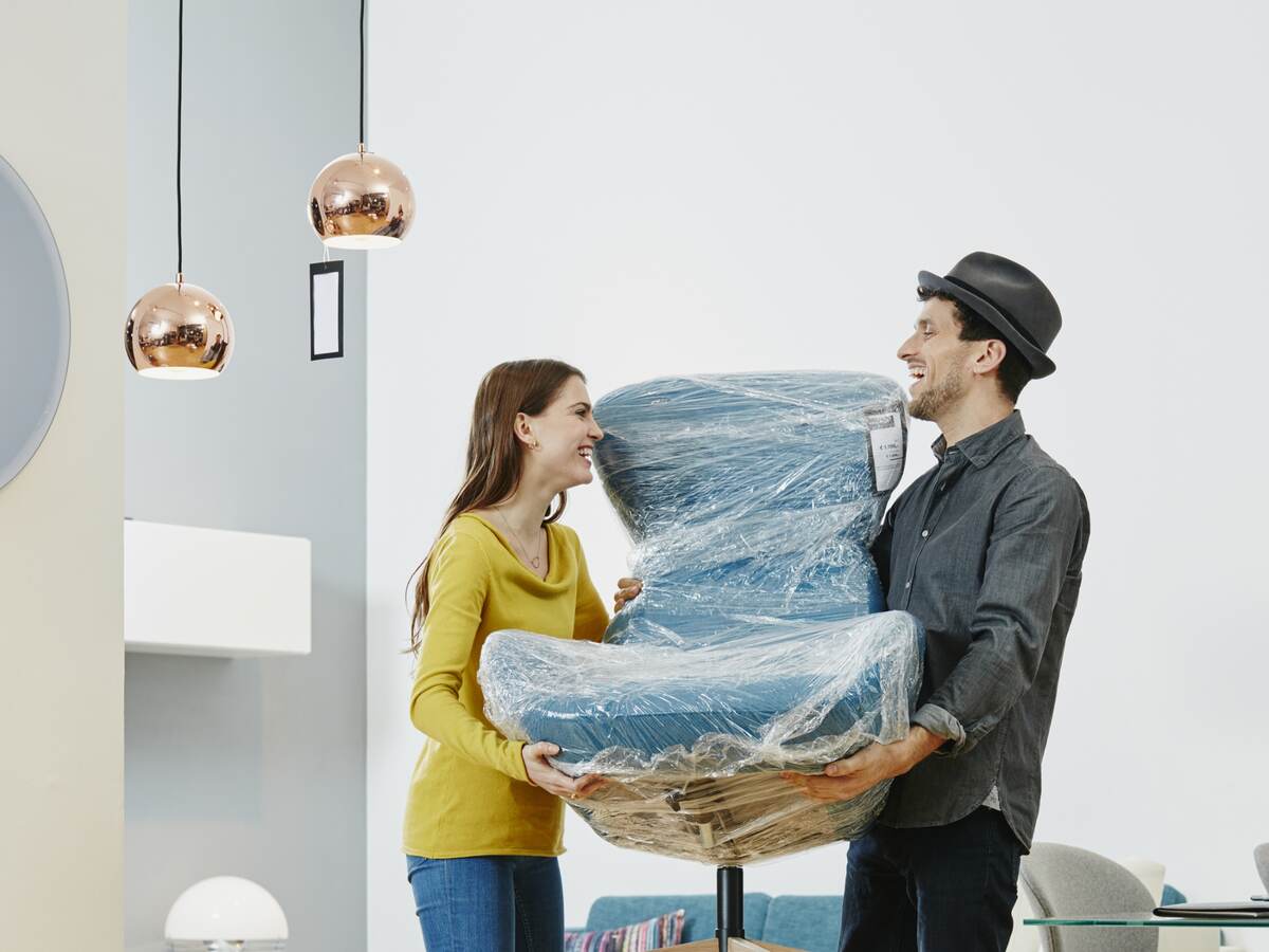 Couple carrying new arm chair out of furniture store.