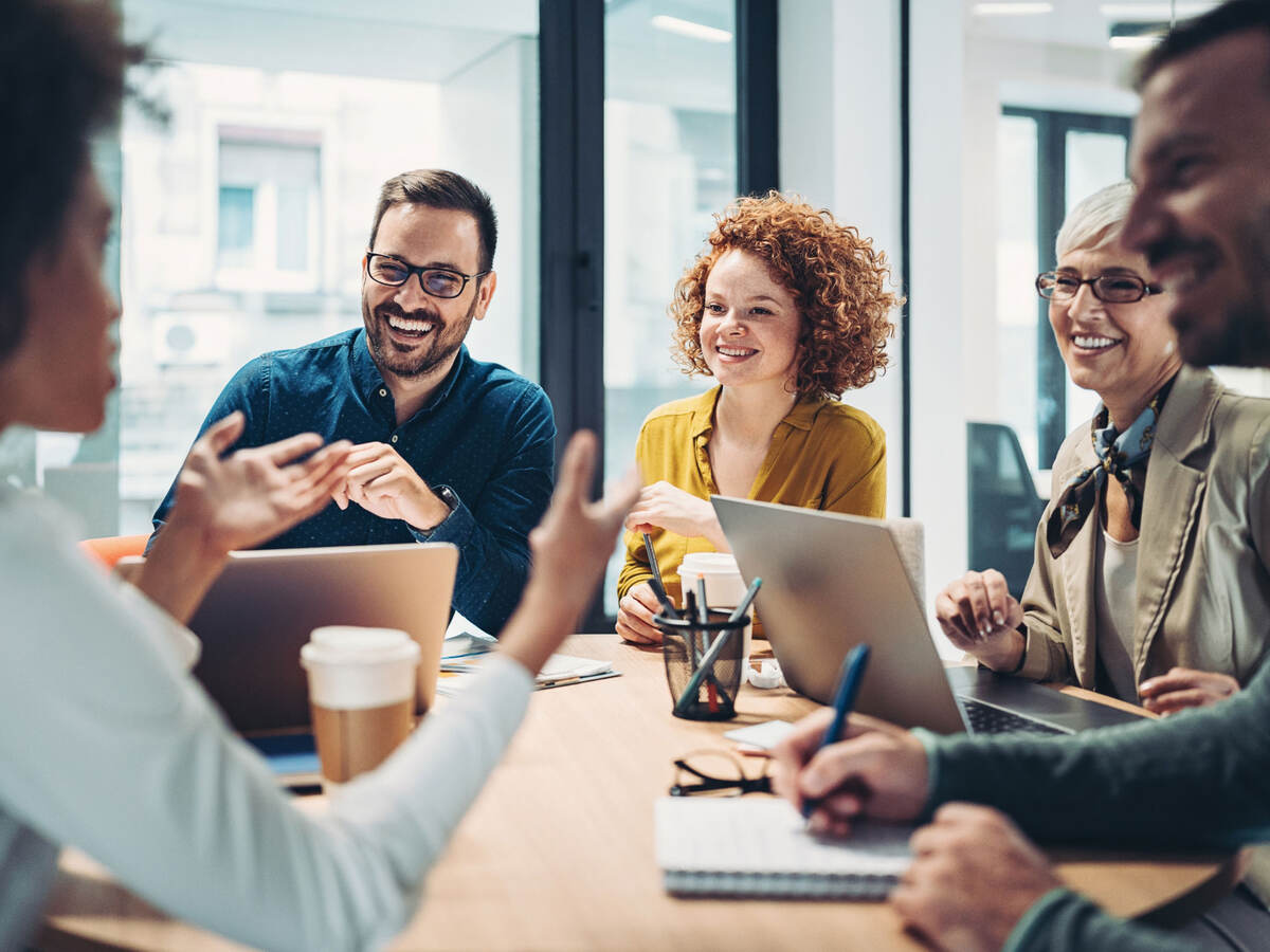 Business people talking in a meeting and using laptops and other devices