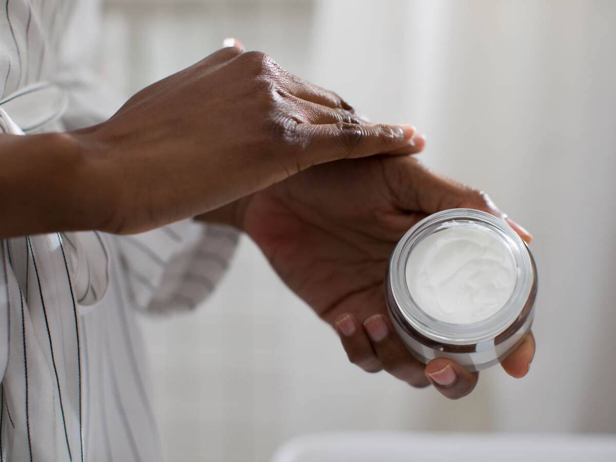 Hands of unrecognizable woman holding cosmetic cream.