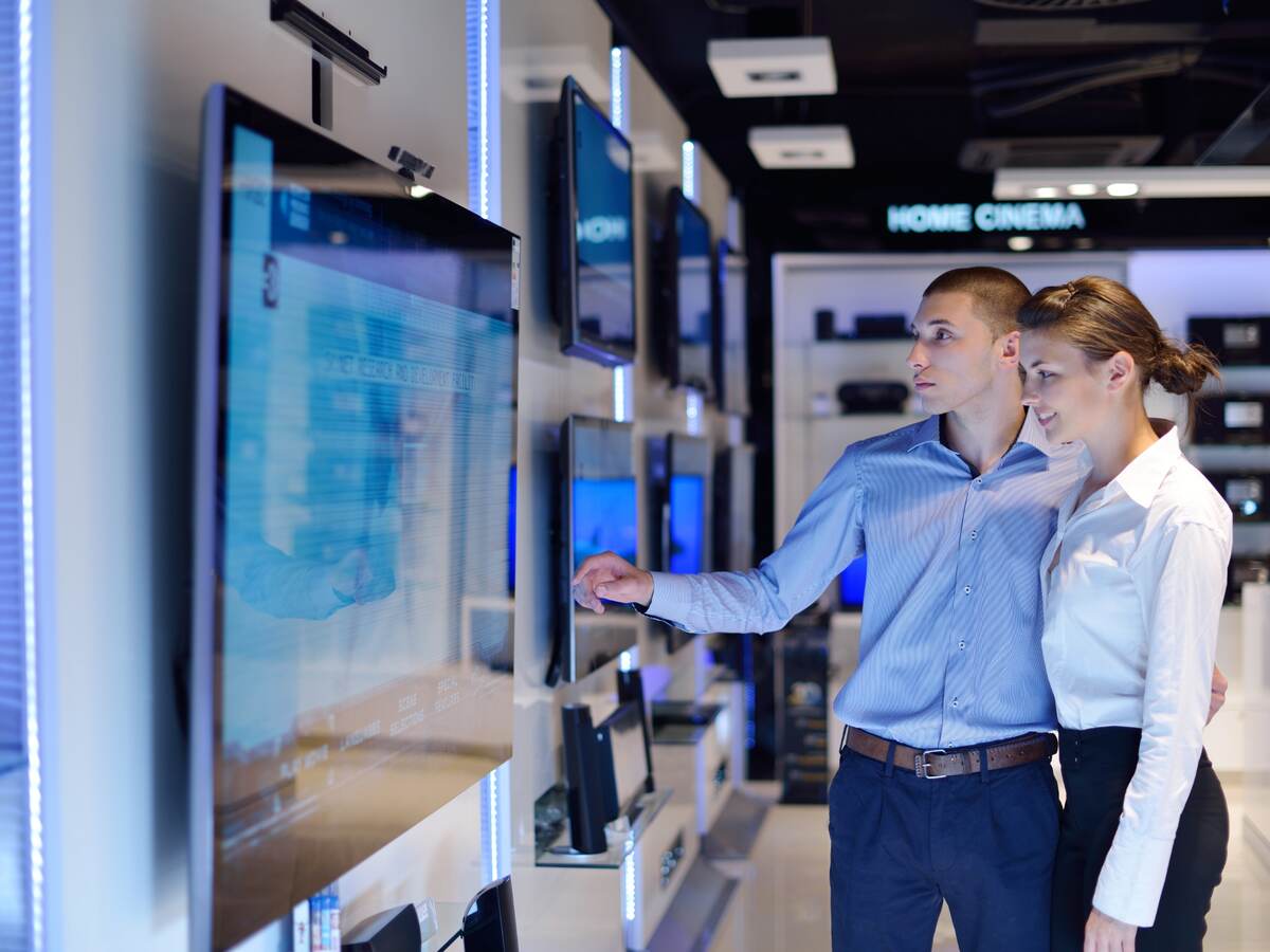 Young couple shopping for a tv in an electronic store.