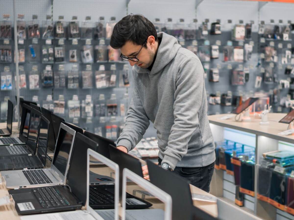 Modern male customer choosing laptop in the computer shop.