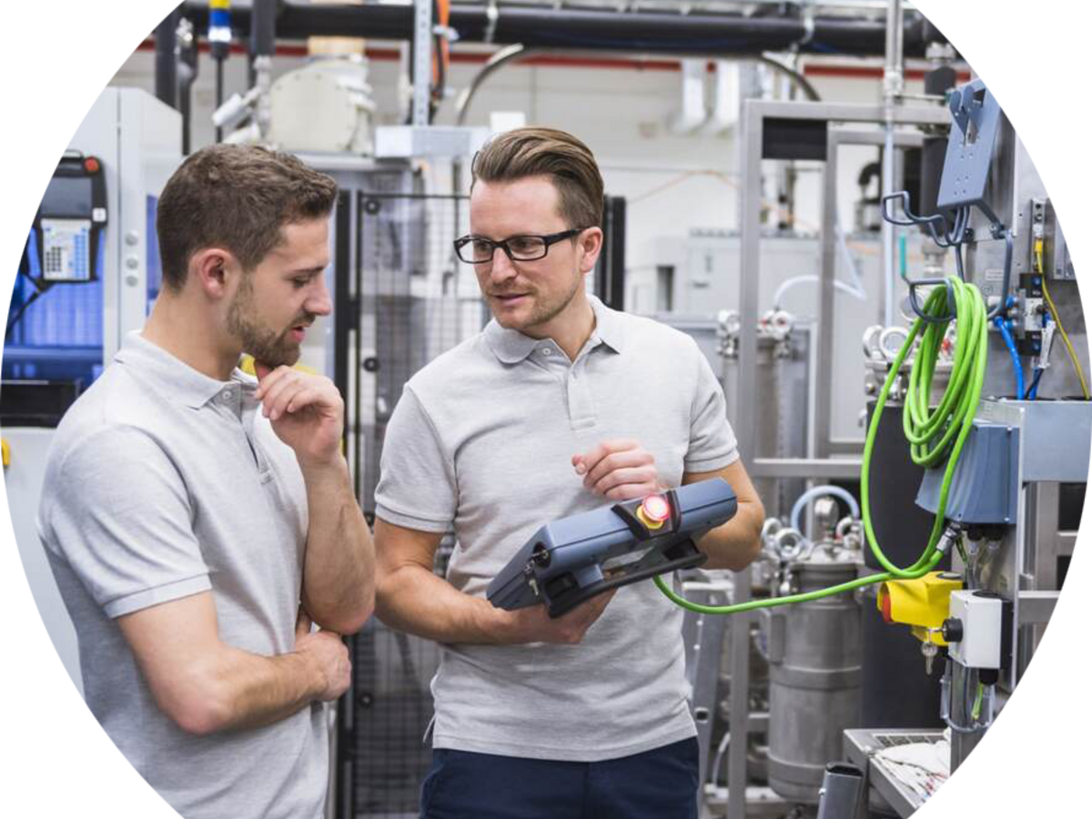 Two engineers working with a control system on factory shop floor