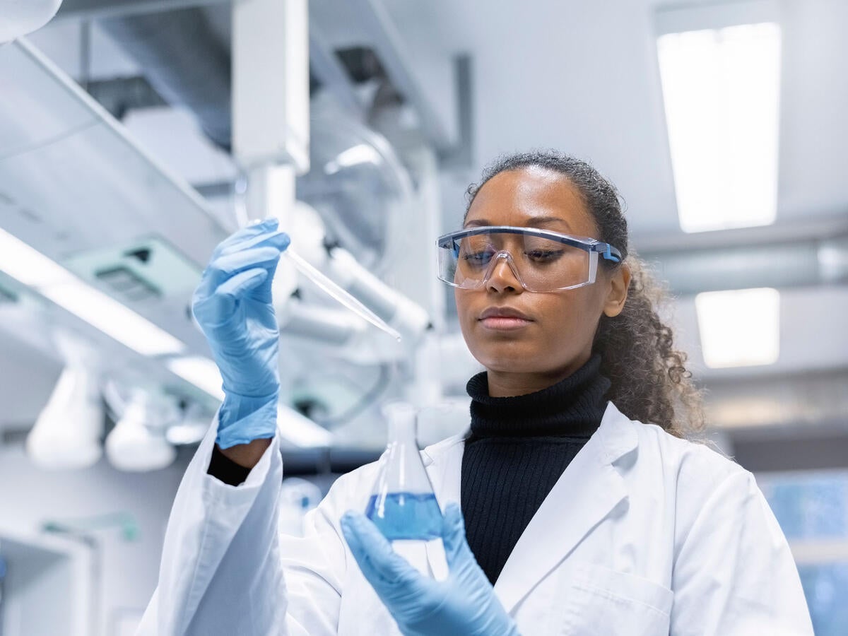 Chemist adding a sample to a solution in conical flask