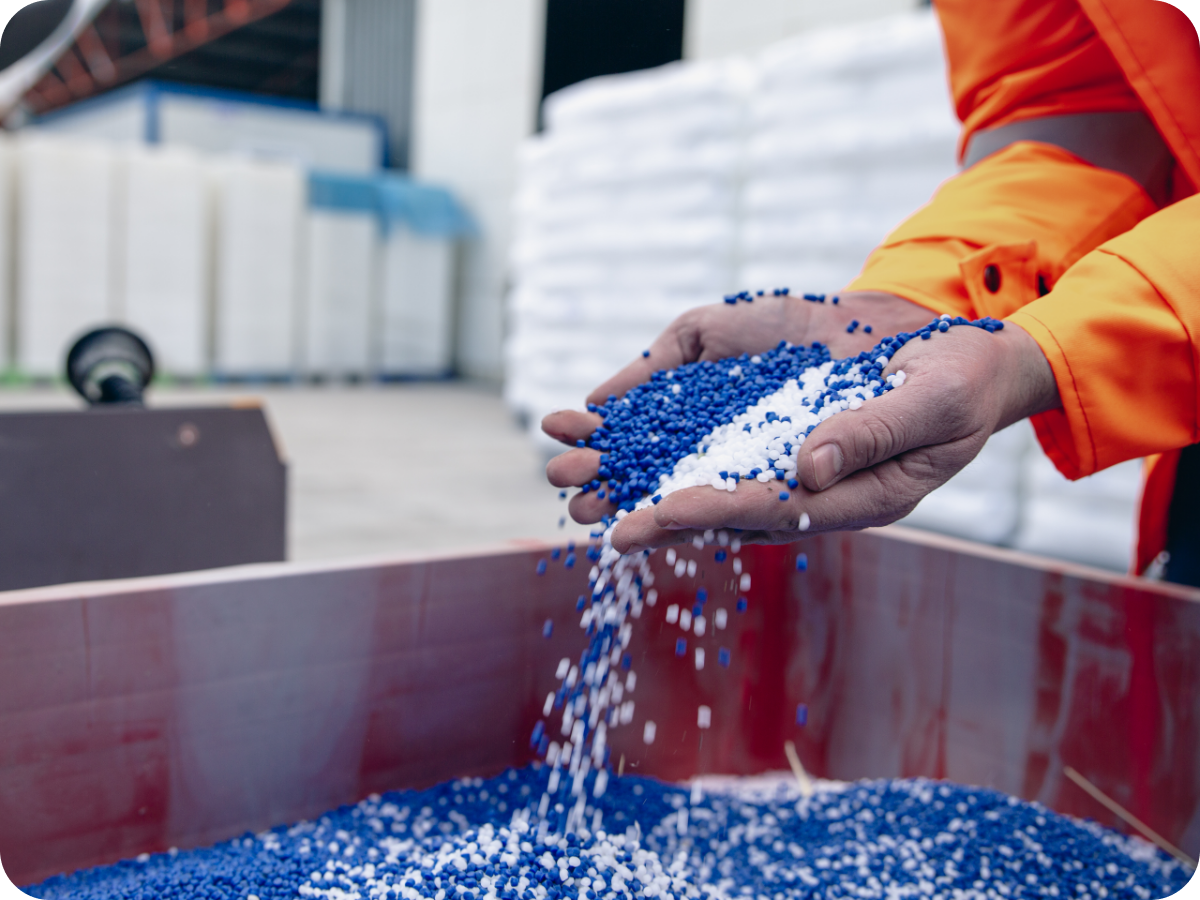 person in warehouse picking up handfuls of blue and white chemical pellets