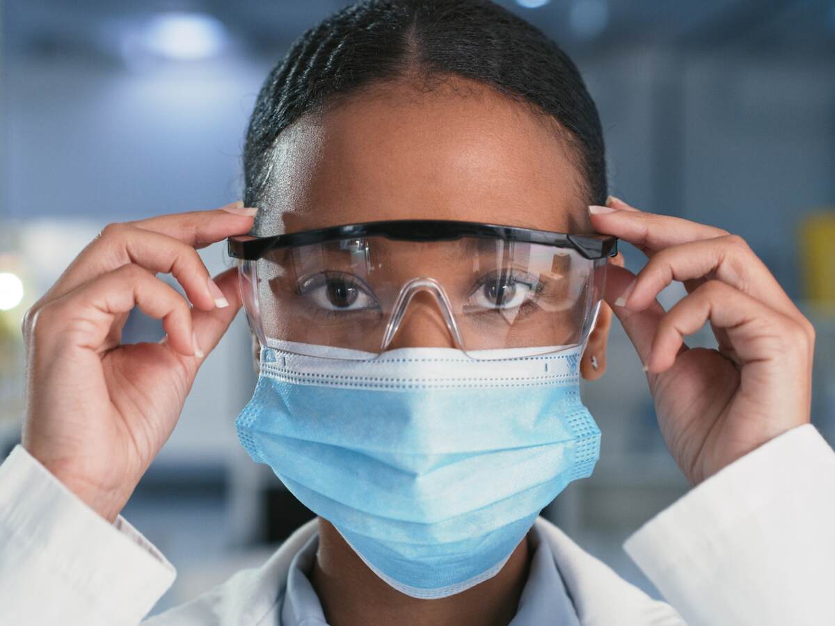 Shot of a confident scientist taking her goggles off while wearing a face mask in a modern laboratory