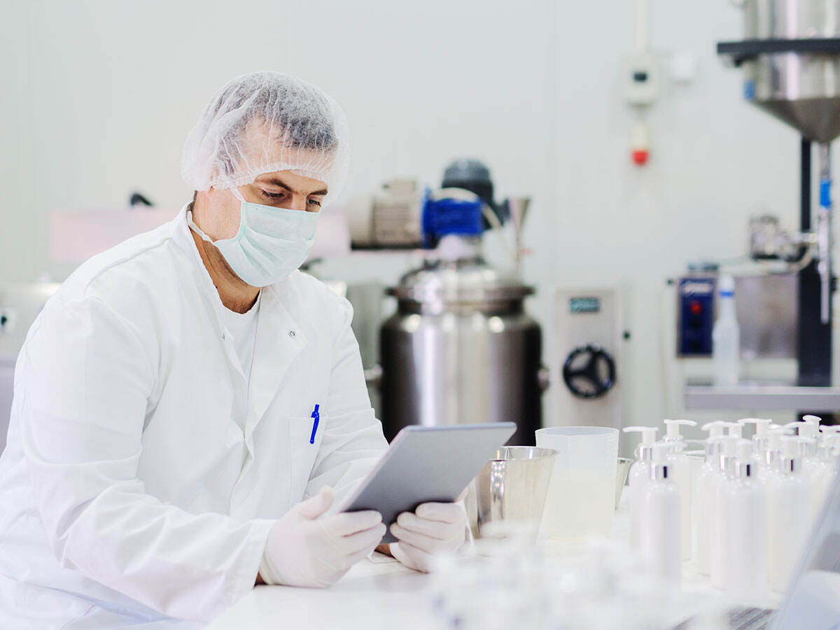 Scientist looking at a tablet while sitting in the lab in front of samples
