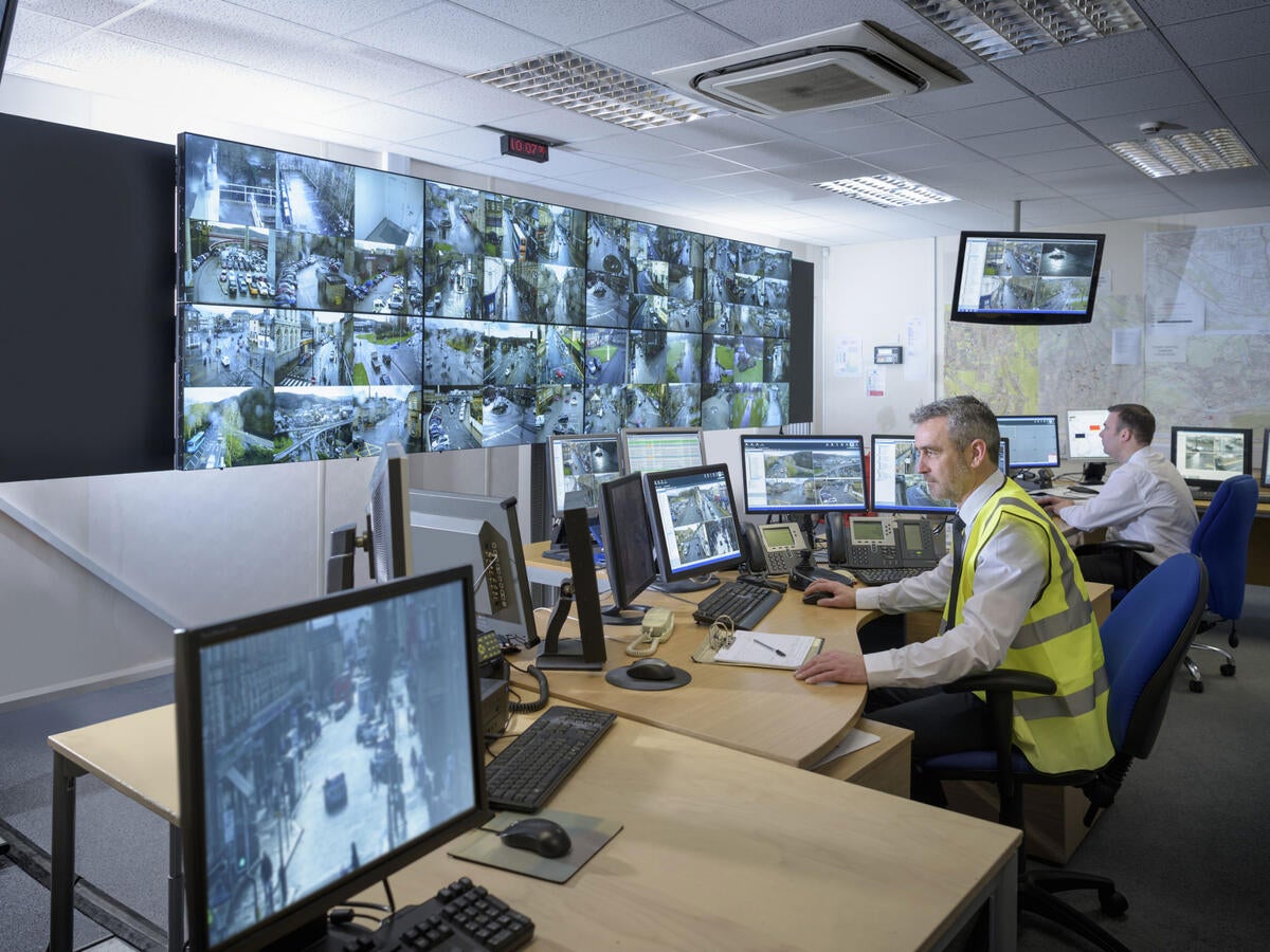 A security guard watching several monitors