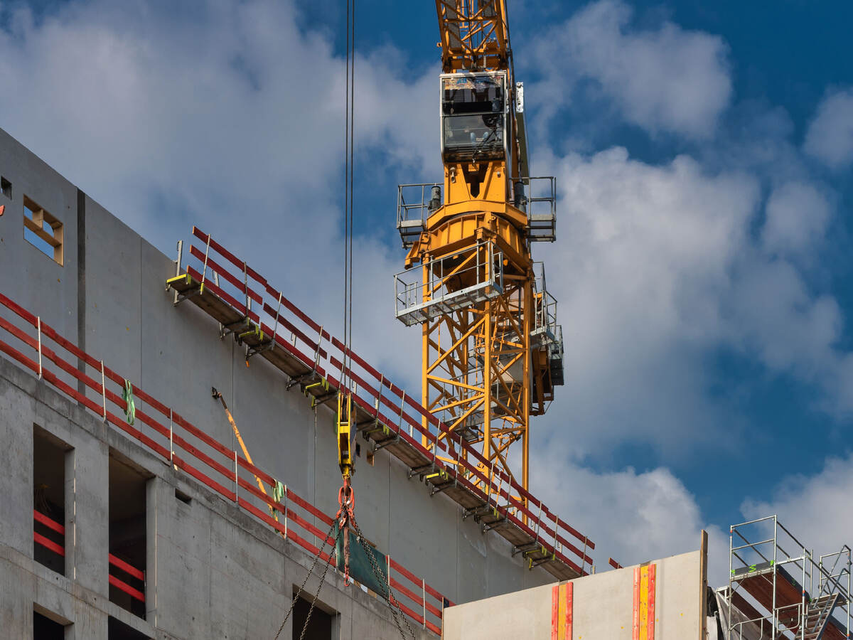 A crane on top of a building hoisting a heavy object