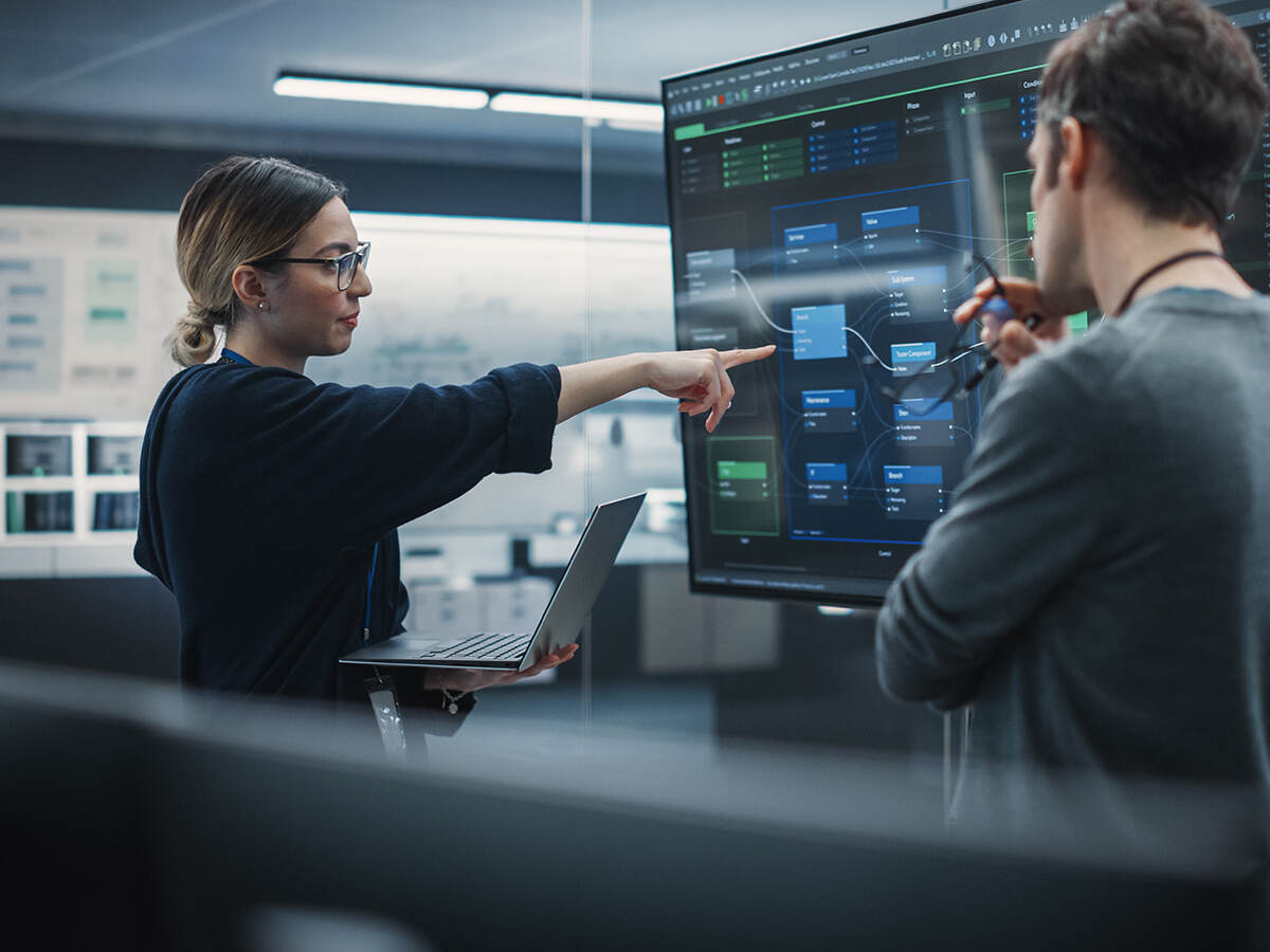 Two people reviewing data on a large screen