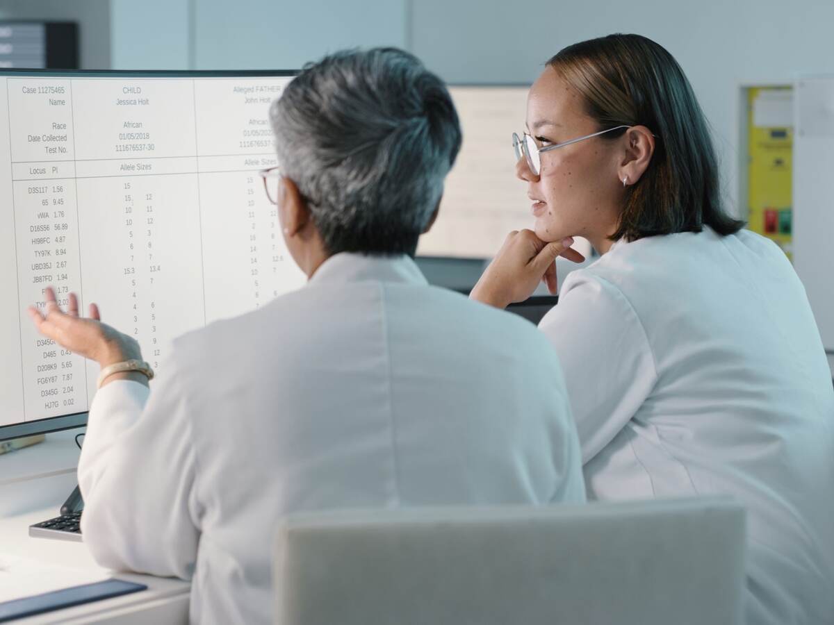 Two doctors look at a list on a computer monitor