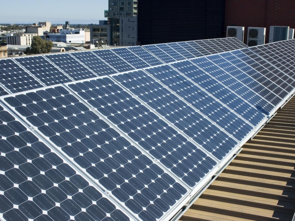 Solar panels on company rooftop with city in background