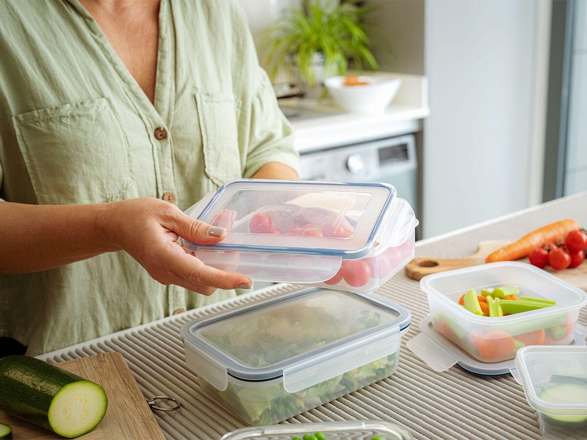woman storing vegetables in glass container