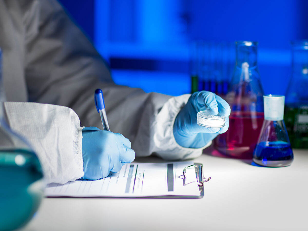 A chemist writing on a paper on a clipboard