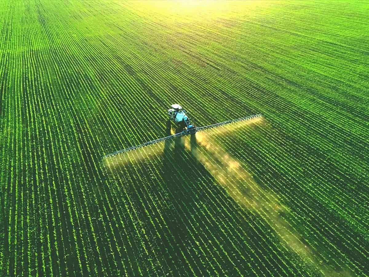 A tractor spraying fertilizer on a green field