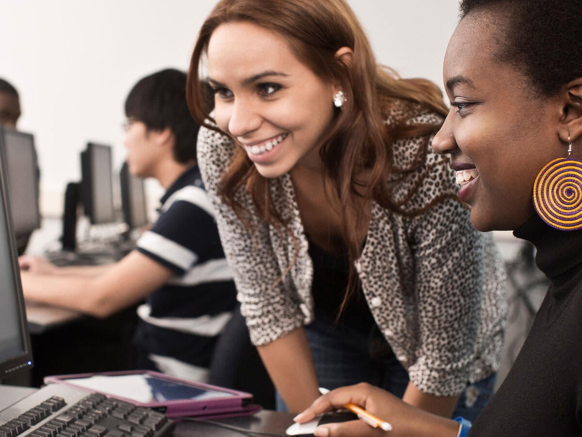 Two smiling people looking at a computer screen