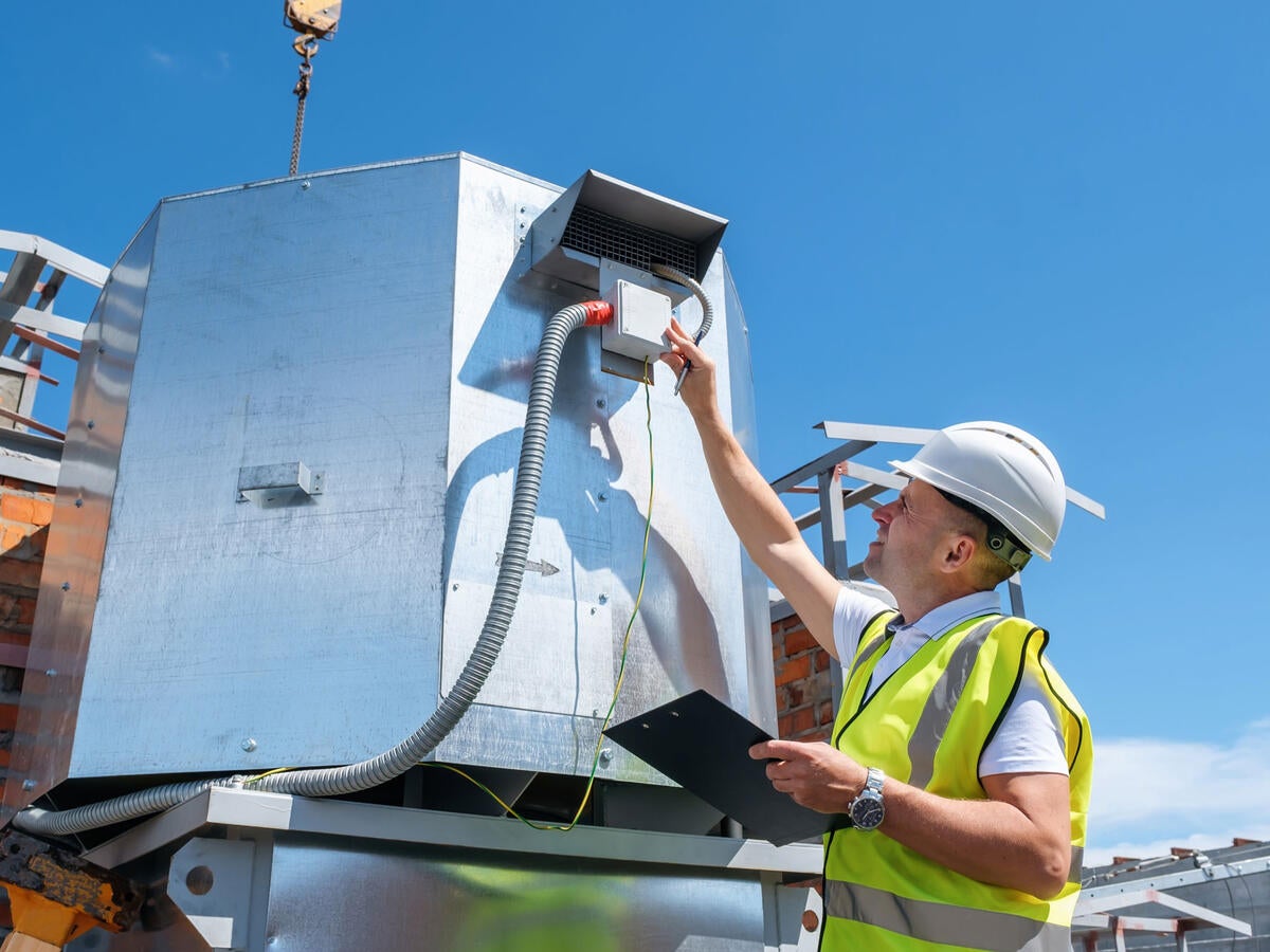 Engineer with clipboard checking the installation of the ventilation system
