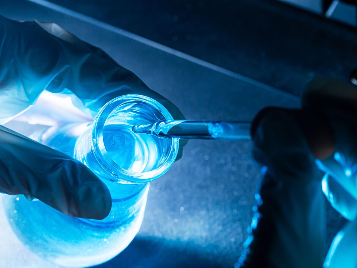 A lab technician pipetting liquid into a flask