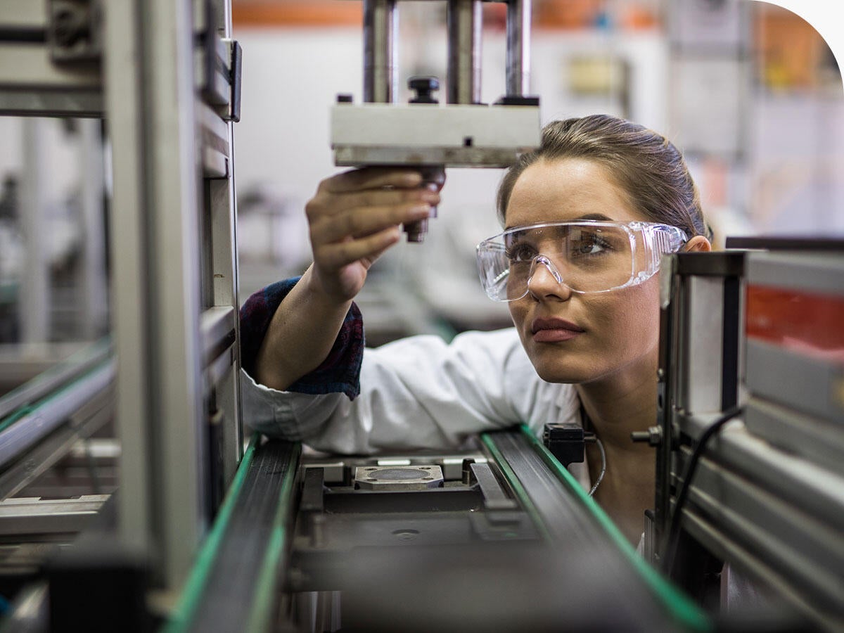 Quality control worker analyzing machine part on a manufacturing machine.