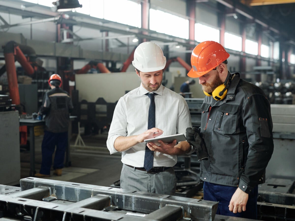Manager and engineer looking at a tablet together on a factory floor