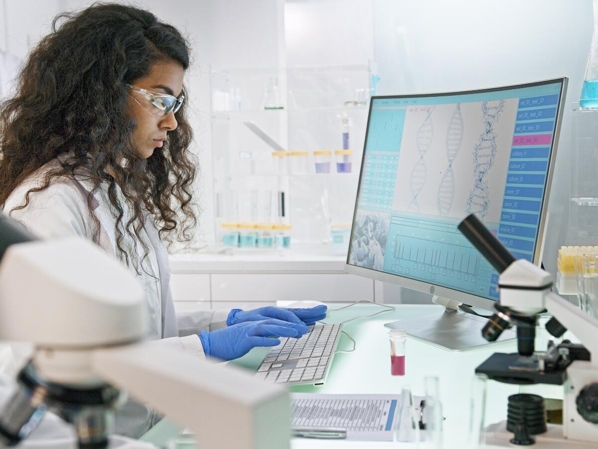 scientist in lab looking at DNA model on computer